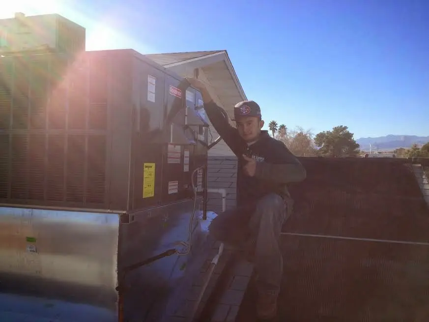 HVAC technician performing HVAC Inspection on a rooftop unit in Lansing